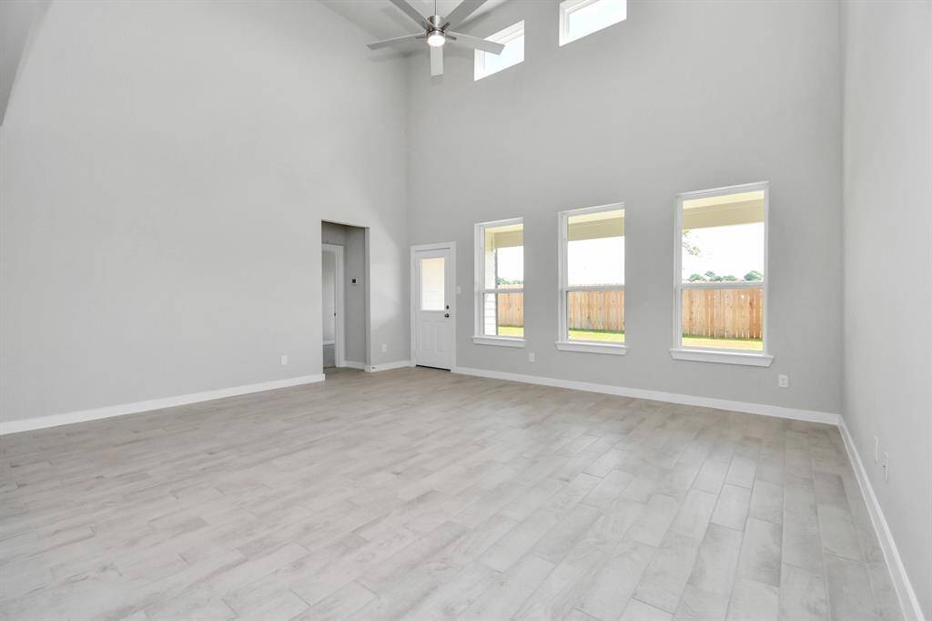 Bring your loved ones and guests together in the inviting living room! Boasting lofty high ceilings, recessed lighting, a stylish ceiling fan, custom paint, stunning flooring, and expansive windows that flood the space with ample natural light all day long. Sample photo of completed home. Actual colors and selections may vary.