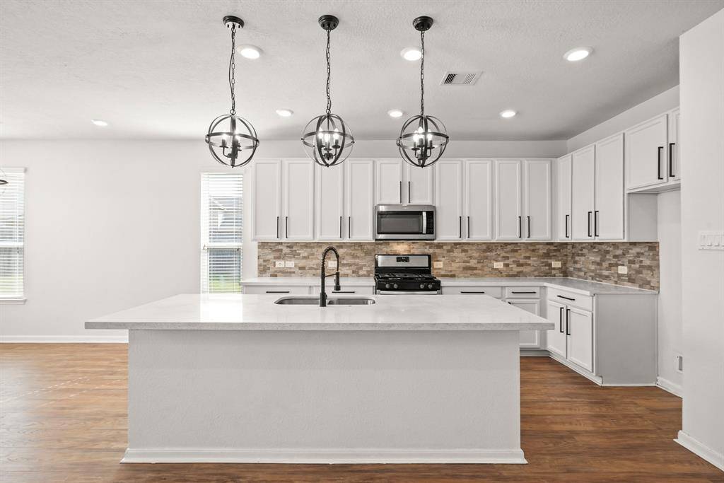 Modern kitchen with beautiful light fixtures, a spacious eat-in island, and plenty of counter and cabinet space
