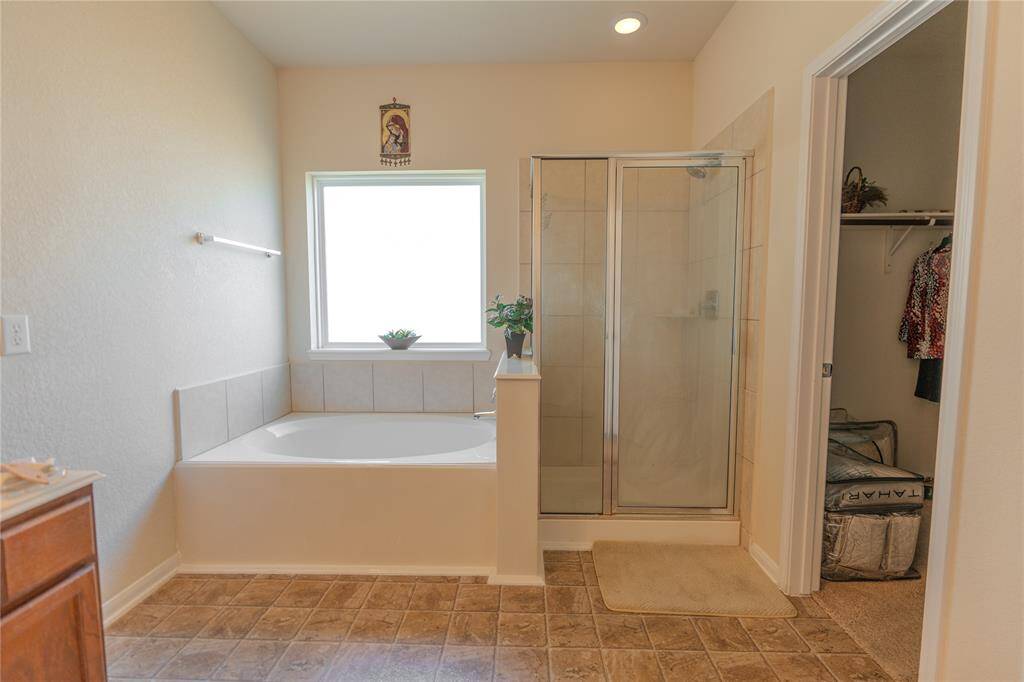 Luxurious primary bathroom featuring a relaxing soaking tub and a spacious separate shower.