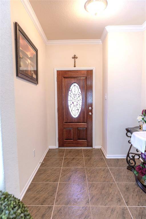 Welcome your guests with this inviting foyer, featuring elegant tile flooring and a beautifully crafted wooden door.
