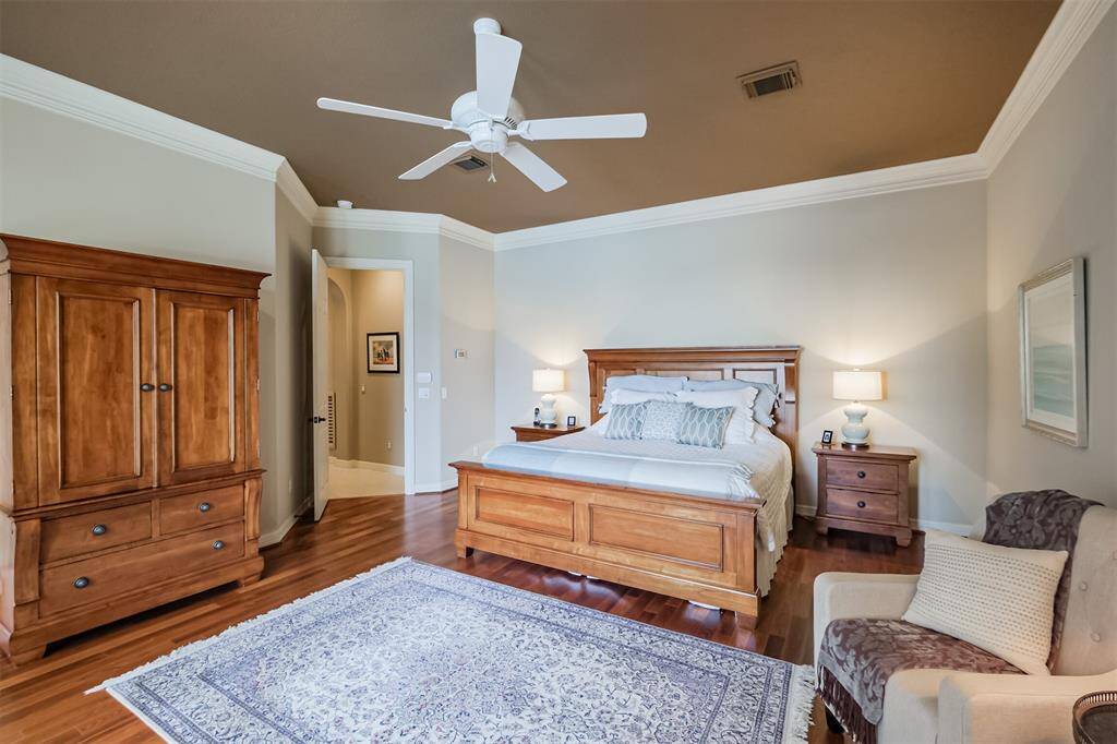 The serene primary retreat features hardwoods, double crown molding and ceiling fan.