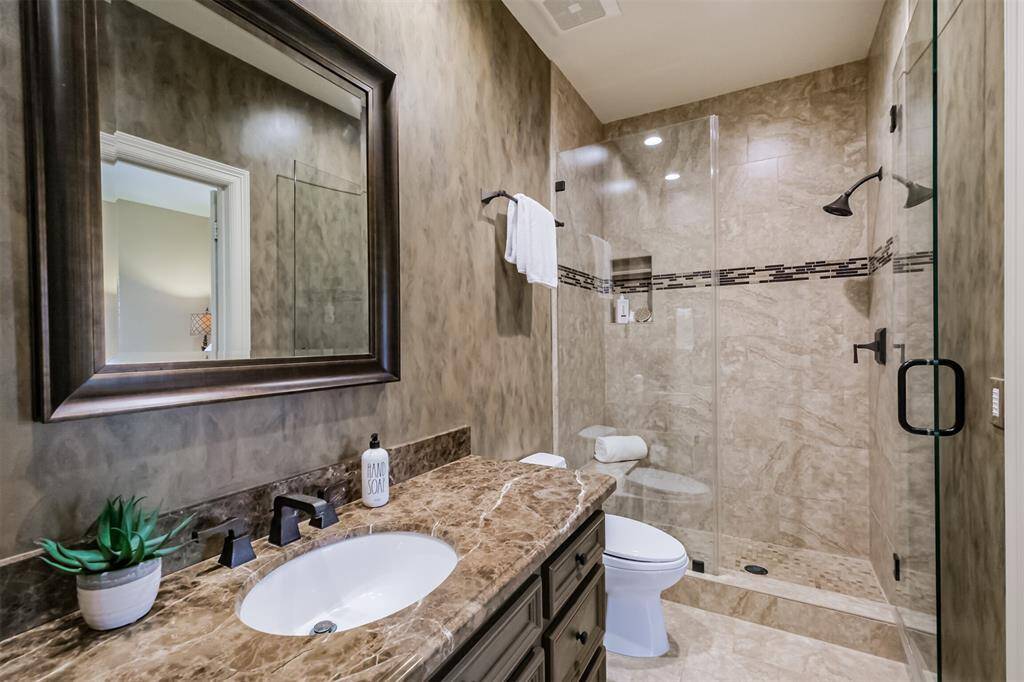 This bathroom features a glass enclosed walk-in shower and granite counters