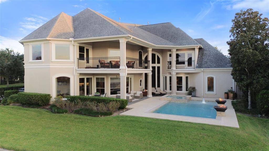 View from the lake's edge of the back of this beautiful home and pool.