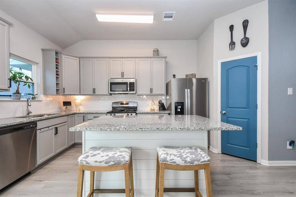 A large island with a granite countertop provides additional counter space and seating.