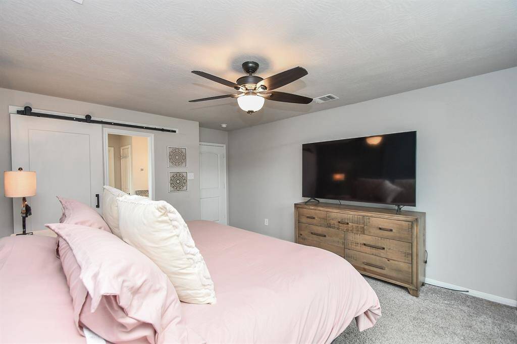 A sliding barn door leads to an en-suite bathroom, enhancing the farmhouse-inspired design.