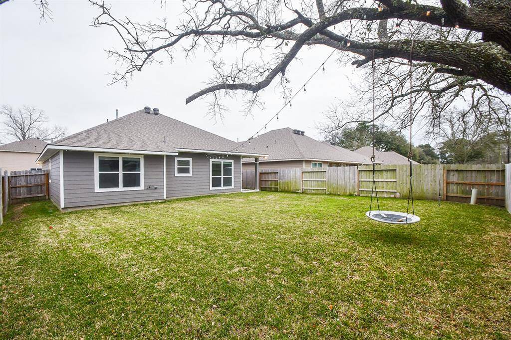 Spacious backyard featuring a majestic, mature oak tree with sprawling branches extending beyond the fence, creating a serene and tranquil atmosphere.