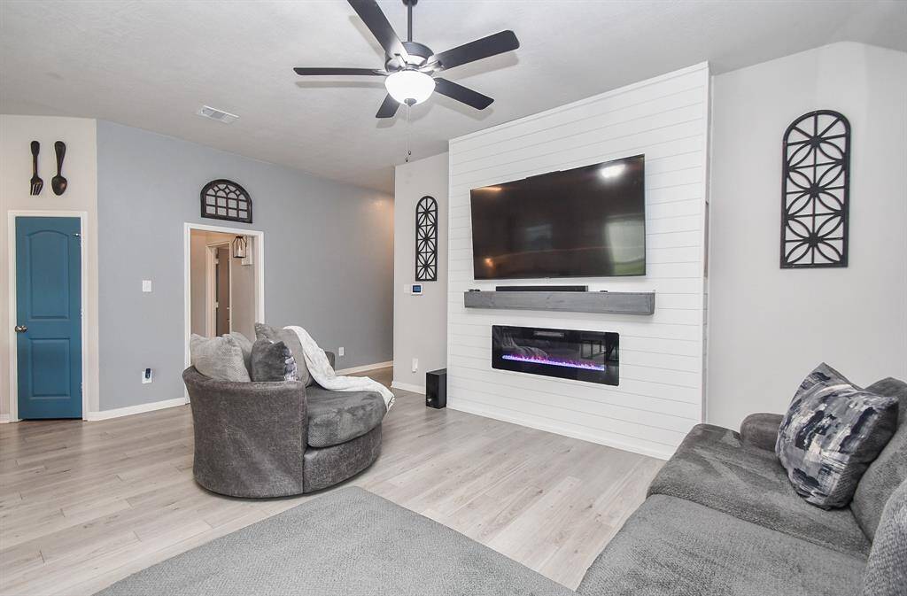 The focal point of this space is a sleek, white shiplap accent mantel a perfect space for you wall mounted TV, featuring a electric fireplace with vibrant flames.