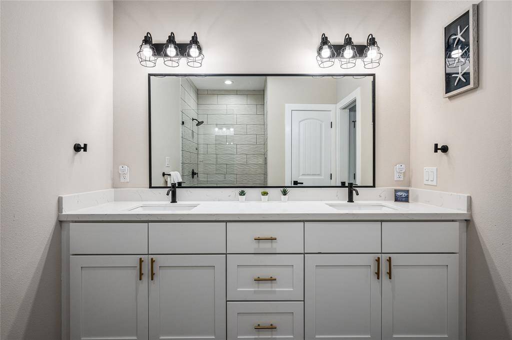 Bath 1: The second-floor primary bath has a double vanity with quartz countertops and a large mirror.