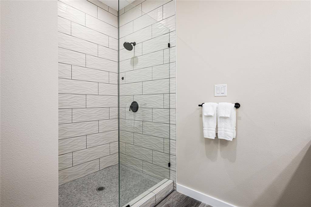 Bath 1: The spacious primary shower is tiled from floor to ceiling.
