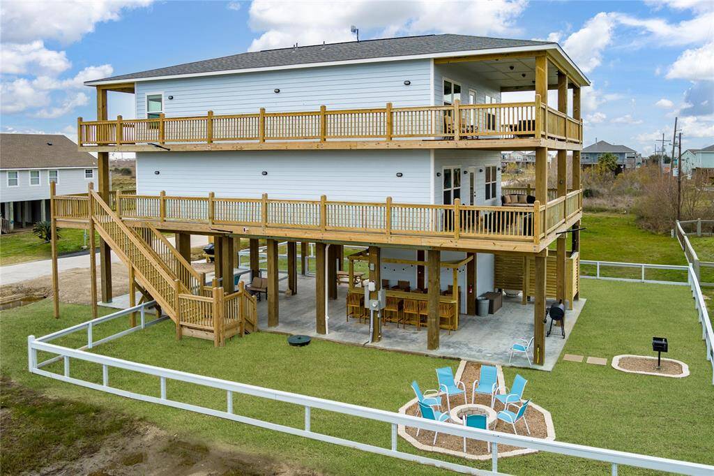 The ground floor is vacation-ready with tiki bar, string lights, fire pit, park-style grill, sand shower, BBQ pit, and one-car garage.