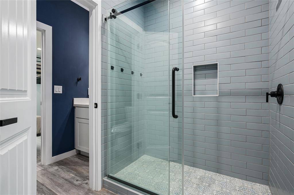 Bath 3: Jack-and-jill shower is tiled floor to ceiling with rolling glass door with accent tile on the floor of the shower.