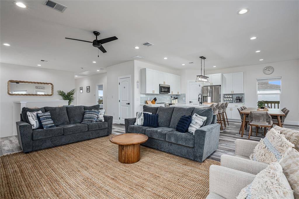 Featuring high ceilings, this airy living room is open to the kitchen and dining area.