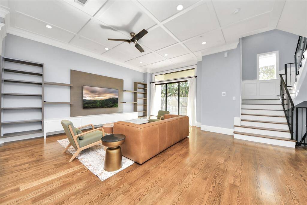 Welcome family and guests to your charming living room! With its high ceilings, recessed lighting, ceiling fan, custom paint, beautiful flooring, and large windows that let in abundant natural light, this room is perfect for gatherings.