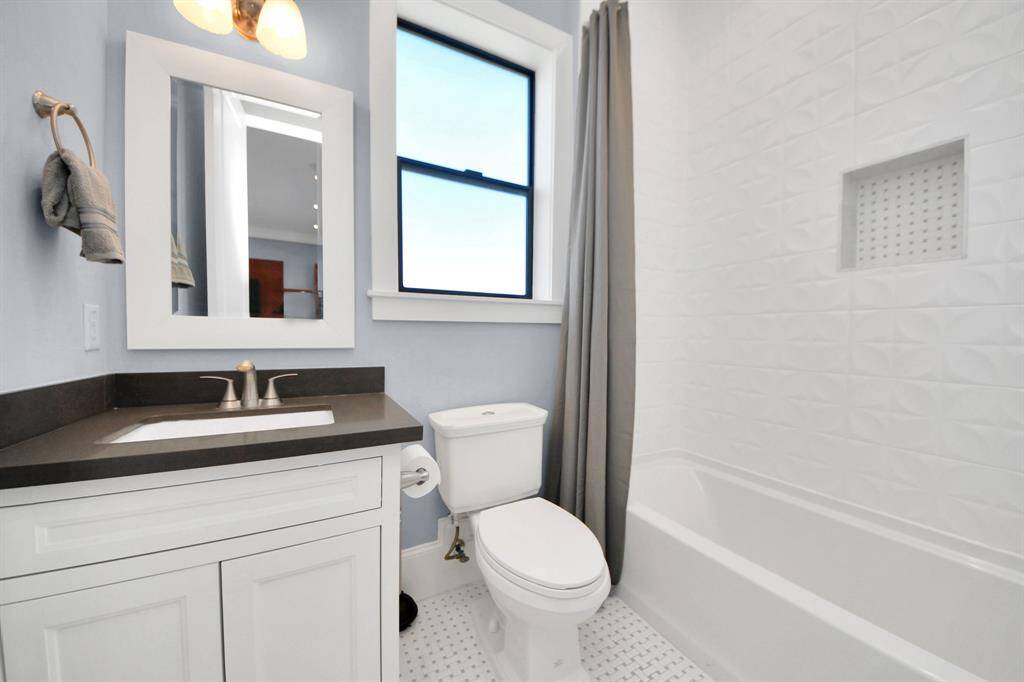 Secondary bath features tile flooring, bath/shower combo with tile surround