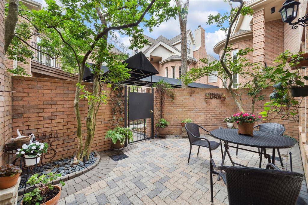 Quaint back patio with a gate opening to covered walkway that leads to 2-car detached garage