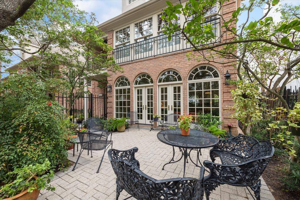 French doors in the formal living room open into this private gated patio that is surrounded by mature landscaping