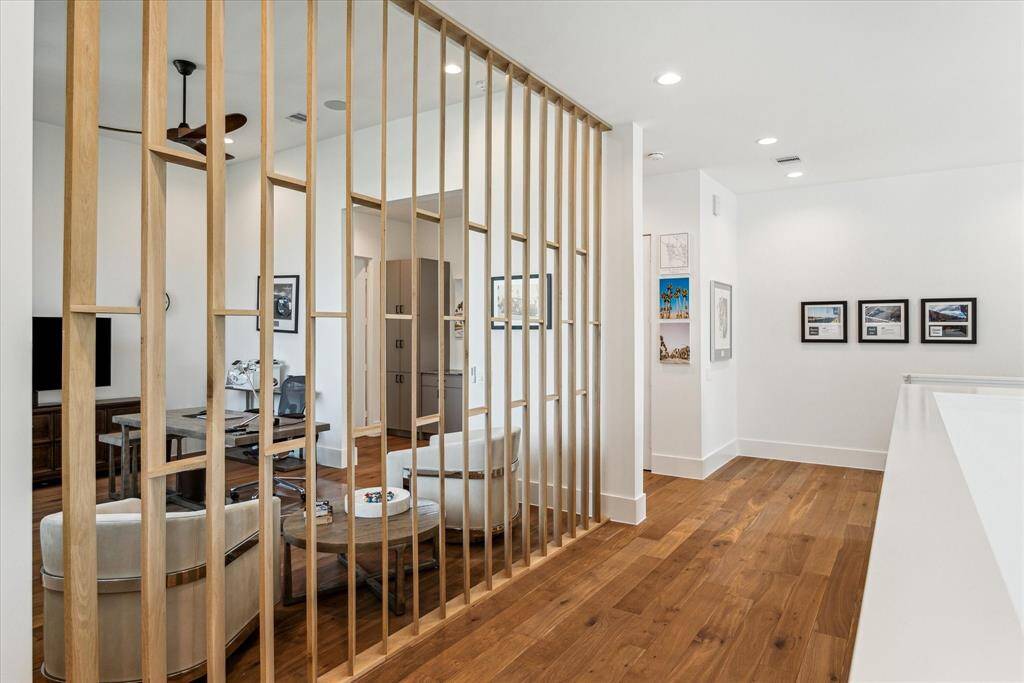 The second-floor landing showcases warm wood flooring and a striking vertical wood slat divider offering a stylish peek into the adjacent study, blending openness with a sense of privacy.