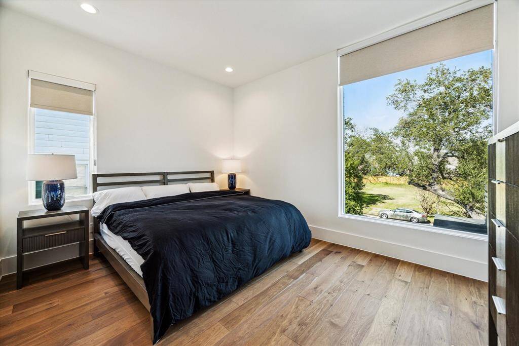 Bedroom #4 offer a bright sanctuary, featuring a large picture window with treetop views and overlooks the front lawn. Wood flooring, recessed lighting, and a walk-in closet complete the room.