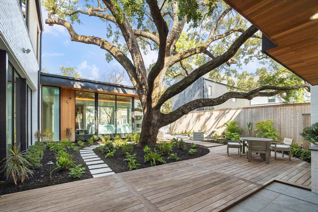 Surrounding a majestic oak tree, the expansive Ipe deck is framed by lush landscaping, and provides a built-in stainless steel grill and multiple seating areas, creating a peaceful setting for outdoor enjoyment and entertaining.
