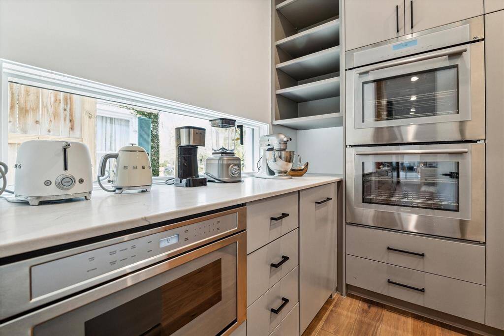 The adjoining scullery offers expanded prep space and exceptional versatility, featuring double Thermador wall ovens, an under-counter Thermador microwave drawer, a second dishwasher, and abundant storage and pantry space—perfect for efficient organization and effortless entertaining.