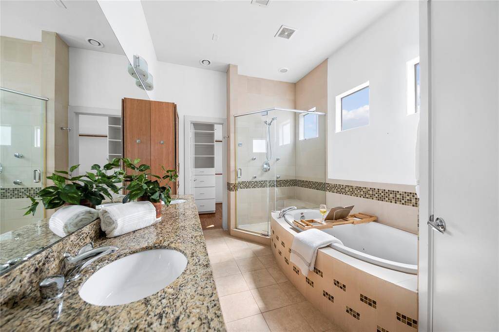 Primary bathroom has dual vanities, a frameless glass shower and jetted tub. Clerestory windows allow for natural light while keeping privacy.