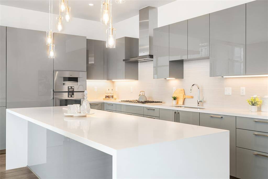 Waterfall edge counters, glass lighting and hidden appliances demonstrate the masterful design of this great kitchen!