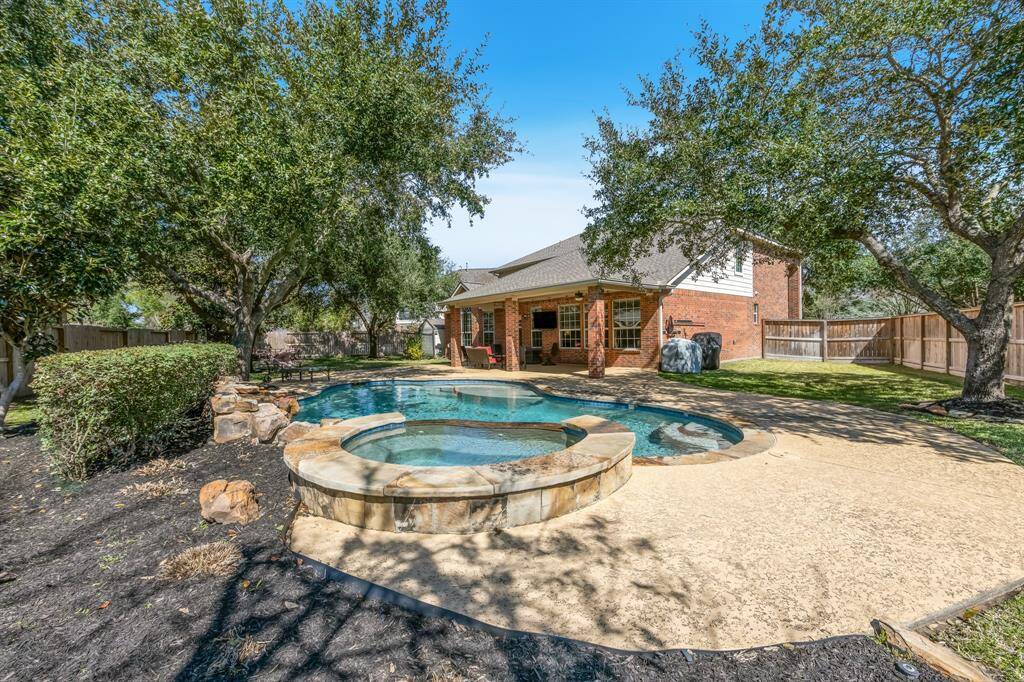 This amazing backyard oasis is a private retreat, featuring a beautiful pool, spa, and lush green space, perfect for relaxation and outdoor entertainment.