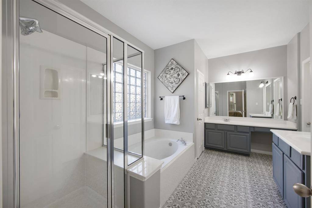 The primary ensuite features his and her vanities with gorgeous painted cabinets, offering plenty of storage and a touch of sophistication. Elegant tile flooring adds a luxurious feel, perfectly complementing the space’s modern and refined design.