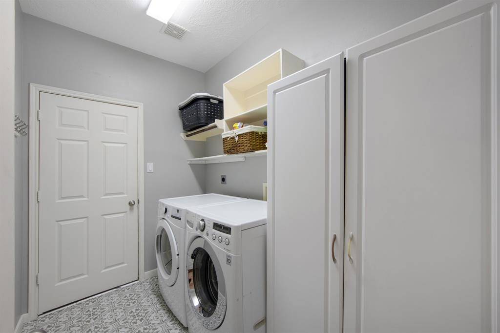 The laundry room is both functional and stylish, featuring gorgeous tile flooring and built-in shelves for convenient storage. It provides an organized space, perfect for tackling household tasks with ease. Also offers ample space for an extra fridge, freezer, or additional storage.