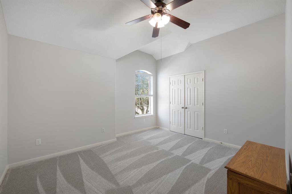 The secondary bedroom is both comfortable and inviting, featuring plush carpeting and a ceiling fan for added comfort and airflow.