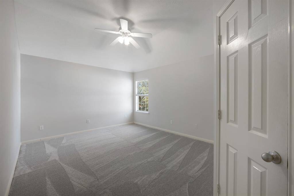 The secondary bedroom is both comfortable and inviting, featuring plush carpeting and a ceiling fan for added comfort and airflow.