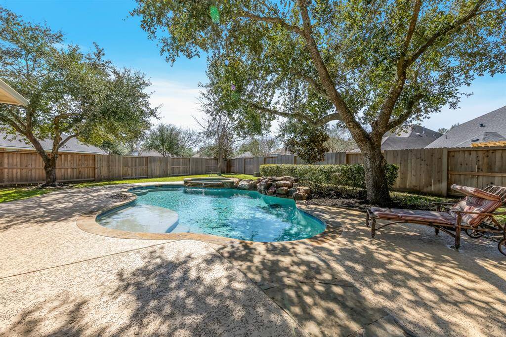 The large backyard features a stunning pool and spa, offering a perfect spot for relaxation and fun. Mature trees provide shade, creating a serene and private atmosphere while enjoying the outdoor space. The entire fence was replaced in 2023.