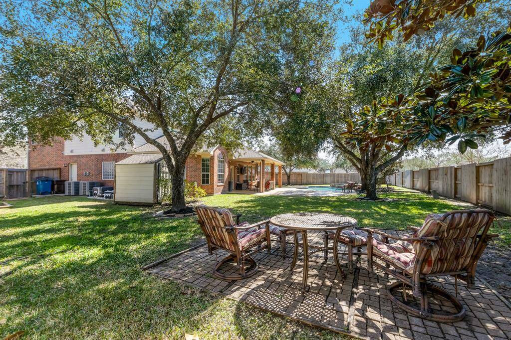 The backyard also includes a practical storage shed with a new roof, providing ample space for tools and equipment. Additionally, a concrete slab is available for the trash cans, keeping them neatly organized and out of sight.