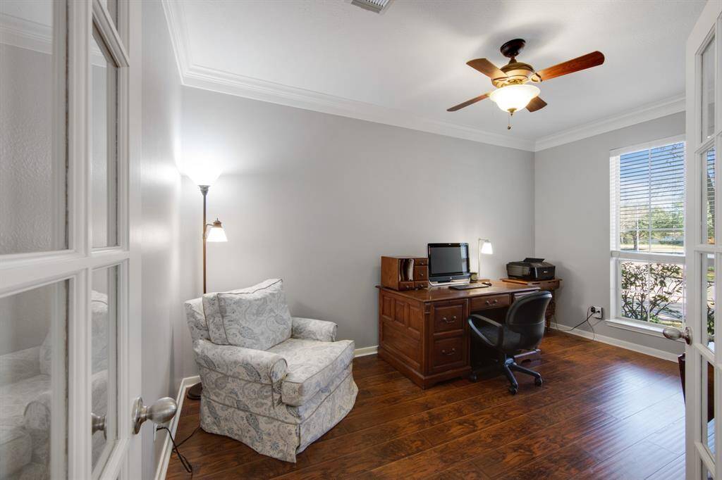 The office is a quiet, elegant space featuring French doors, crown molding, and a ceiling fan, making it ideal for focused work or study. The thoughtful design creates a comfortable and refined environment, perfect for productivity and relaxation.