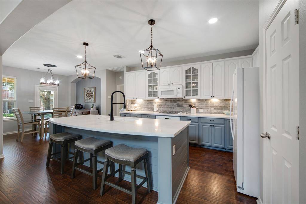 The stunning island kitchen is a true highlight, featuring beautiful Quartz countertops that provide both elegance and durability. Pendant lighting hangs gracefully above the island, which is accented with charming shiplap, creating a stylish focal point. The painted cabinets, enhanced with added hardware, perfectly complement the striking brick backsplash, blending modern design with rustic charm for a warm, inviting space.