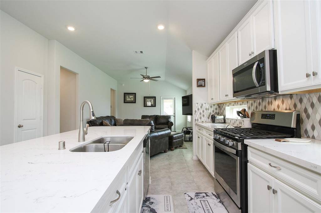 The Kitchen features quartz counters, a pretty back splash, stainless steel appliances, and clean white cabinets with brushed nickel pulls.