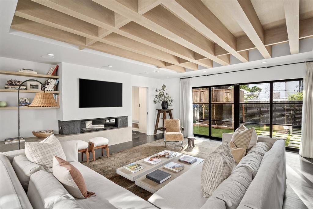Family room with plaster wall and seating, fireplace, white oak ceiling detail, window seat with storage and access to the backyard via sliding doors.