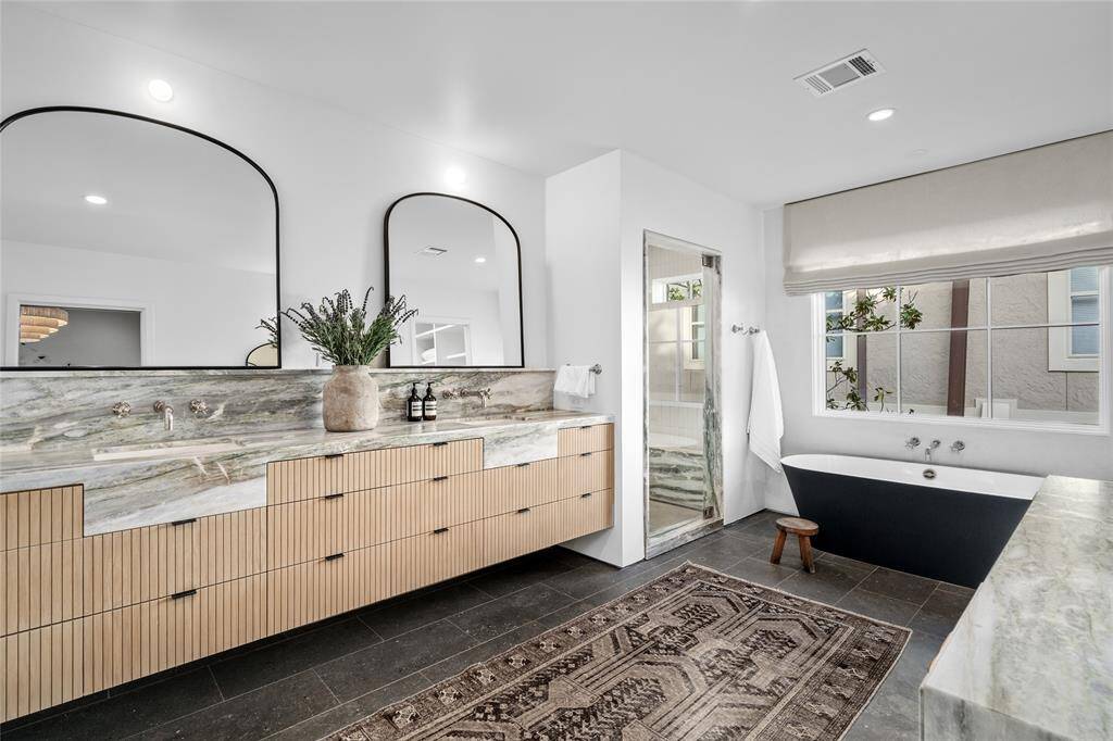 Primary bath with soaking tub, double sinks, vanity, walk-in shower and water closet. Stone from Ann Sacks, white oak cabinet detail done on site, electrical plugs in the drawers