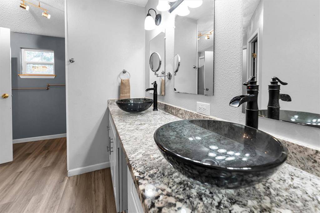 Remodeled primary bathroom with granite countertops and double sinks and vanity
