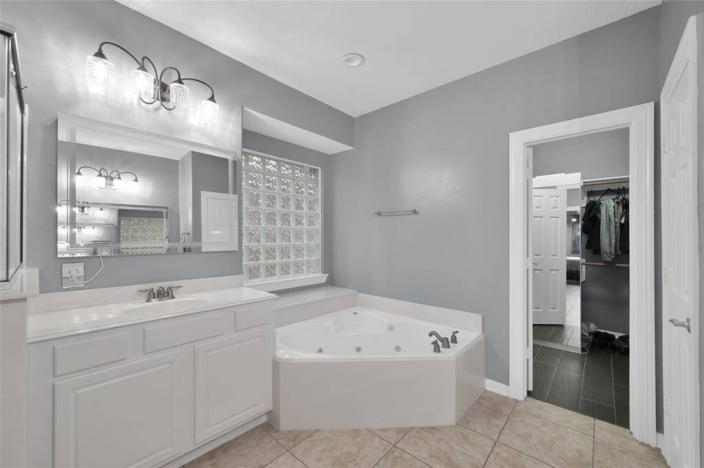 Relax in your new jacuzzi tub. There are two sinks in this primary bathroom and glass block windows.