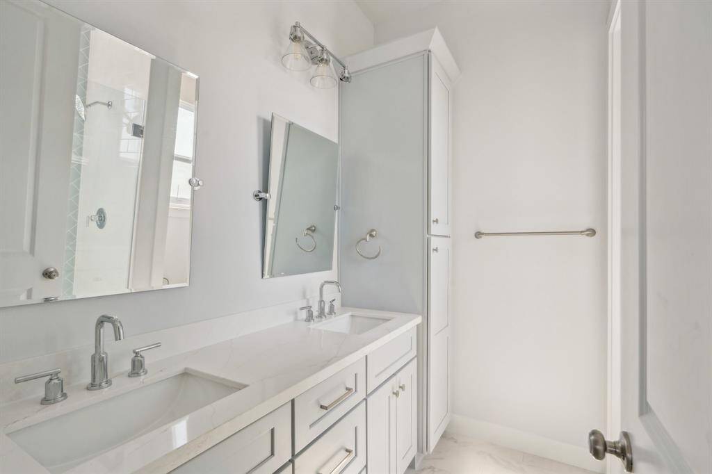 The primary bath with dual vanities, and linen closet.