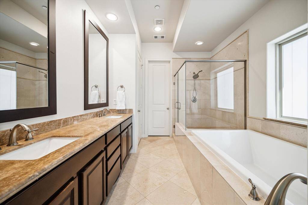 The windowed en suite primary bathroom impresses with a deep soaking tub, a glass shower, a private water closet and a custom walk-in closet.