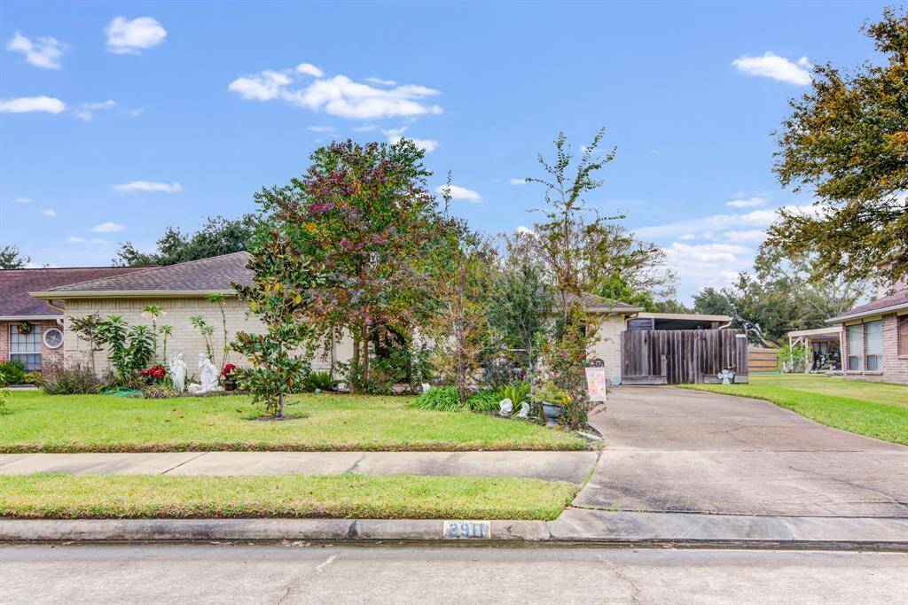Charming single-story home with a well-maintained front yard, featuring mature trees and lush greenery.