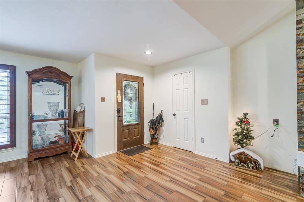 This inviting entryway features wood-look flooring, a decorative glass front door, and ample natural light.