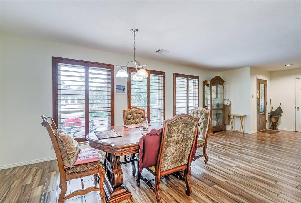 Bright dining area with large windows, wood like flooring, and will accommodate a large table