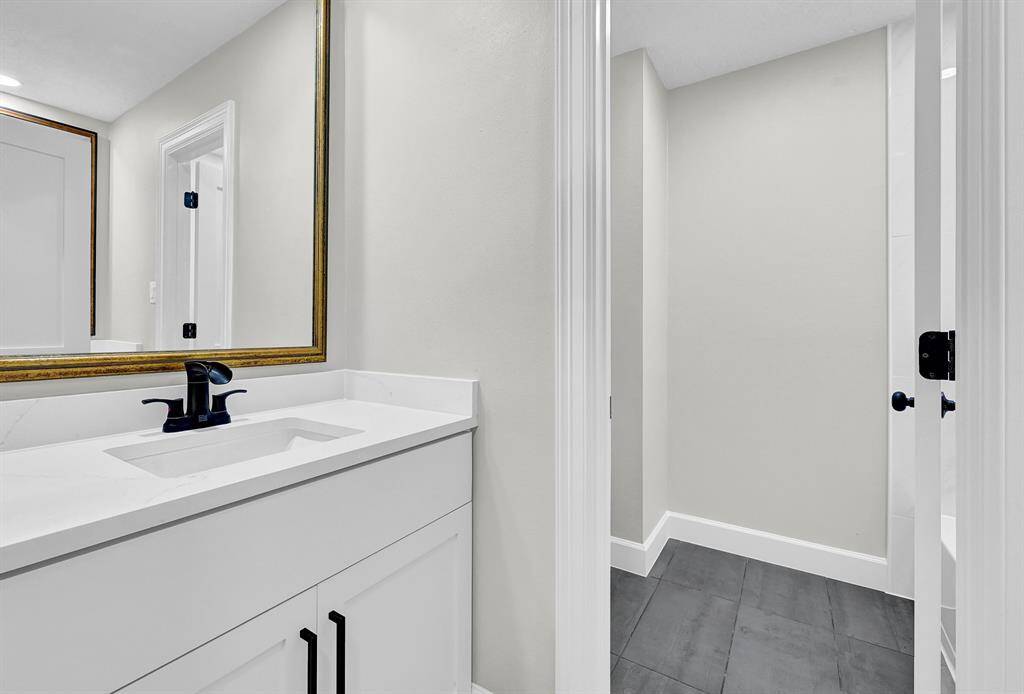 This well-designed second bathroom features a dual-sink layout with vanities positioned back-to-back, offering convenience and privacy for multiple users. With modern quartz countertops, sleek fixtures, and a separate shower area, this space combines functionality with contemporary style.
