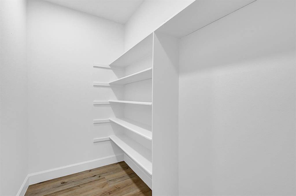 This versatile extra storage room, located at the end of the hallway near the bedrooms, offers ample shelving for organization. Perfect as a walk-in pantry for canned goods and dry ingredients or a custom closet for additional storage, this space adds convenience and functionality to the home.