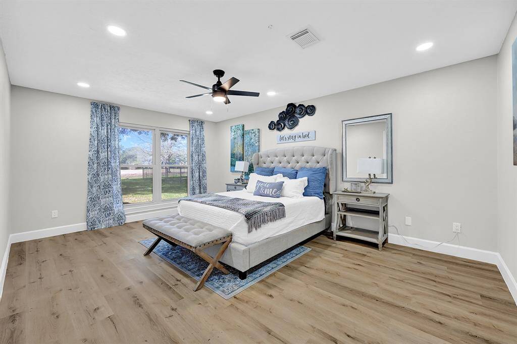 This spacious master bedroom offers breathtaking golf course views through large picture windows, filling the space with natural light. Featuring recessed lighting, a modern ceiling fan, and elegant flooring, this serene retreat combines comfort and luxury.