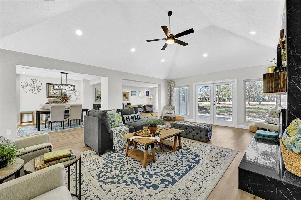 This stunning open-concept living space boasts soaring vaulted ceilings, abundant natural light, and elegant newly installed recessed lighting for a bright and airy feel. The expansive golf course view through the large glass doors creates a seamless indoor-outdoor experience, perfect for relaxation and entertaining.
