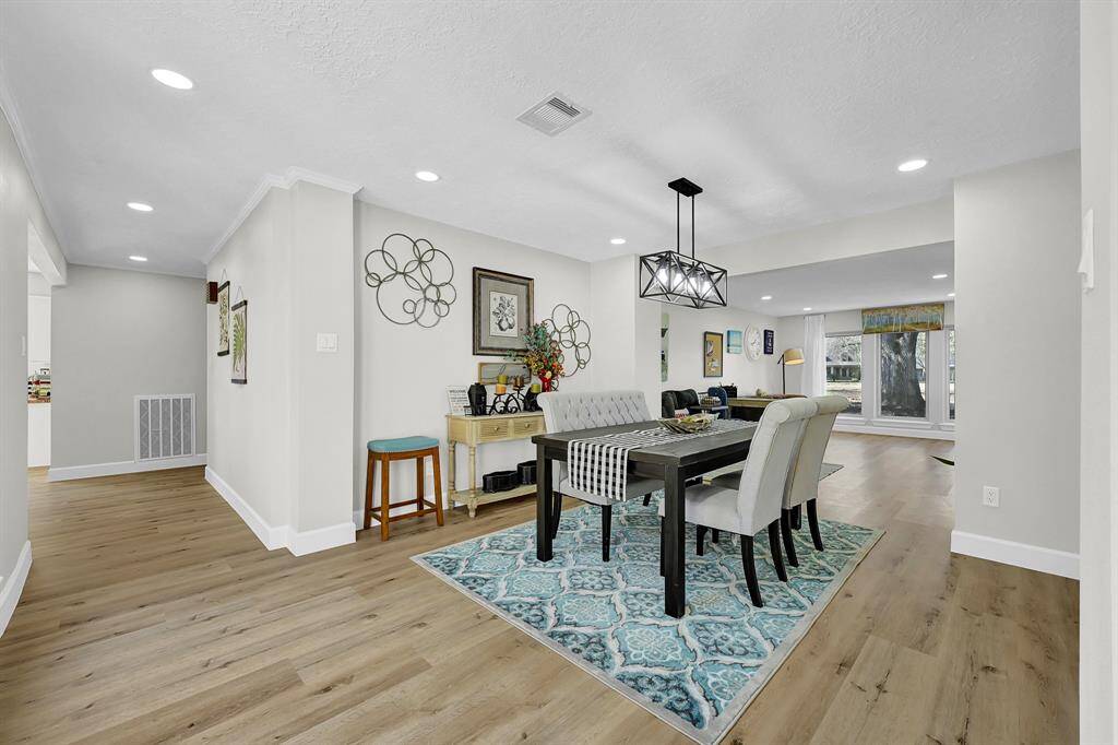 The dining area, conveniently located adjacent to the living room, is defined by a striking light fixture that hangs elegantly above the table. Large windows allow natural light to flood the space, enhancing its bright and airy feel. This open, inviting atmosphere makes it an ideal spot for meals with loved ones or entertaining guests.